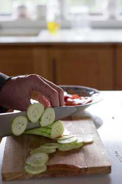 Hombre cocinando, esta cortando en rodajas un pepino