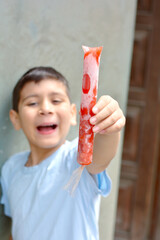 Happy latin boy holding fruit ice.