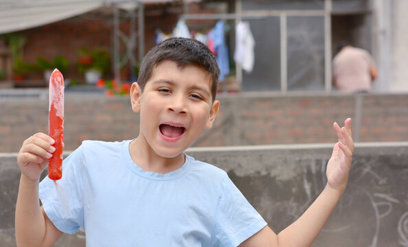 Happy latin boy holding fruit ice.
