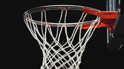 A dynamic closeup shot captures an orange basketball perfectly swishing through a white net on a red rim against a dark dramatic background symbolizing success precision and the thrill of scoring in . - Powered by Adobe
