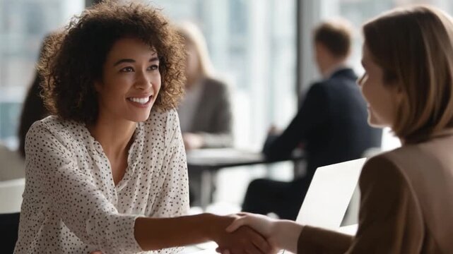 Handshake of Success: An executive female and business female shake hands in a modern office, the scene radiates professionalism, trust and successful cooperation.