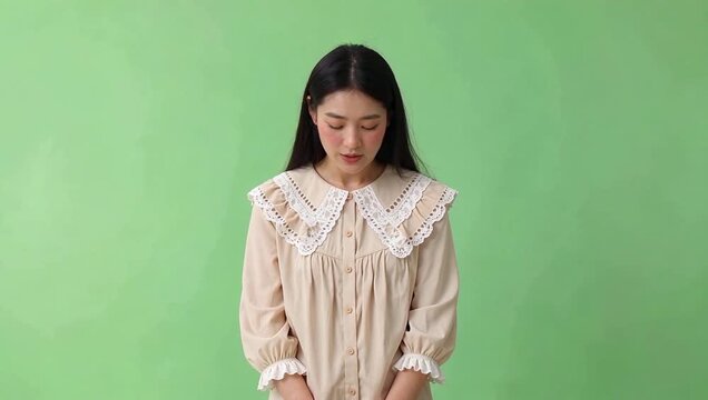 Woman in beige dress with a lace collar against a solid green background