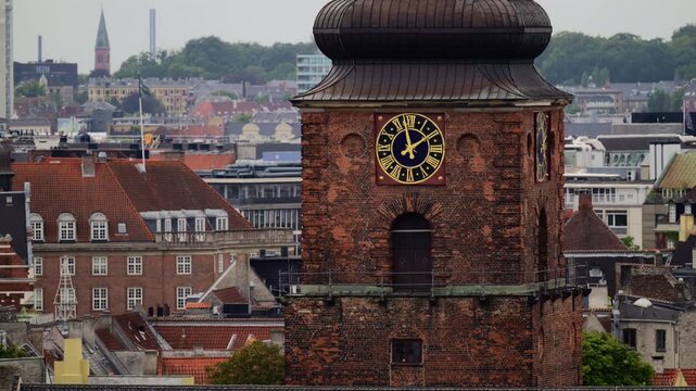 Old brick church clock tower rising above traditional red roof buildings in Copenhagen, Denmark