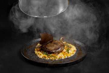 Duck leg with risotto, pumpkin and herbs on a dark background