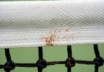 Closeup of tennis net top band showing clay dirt and texture