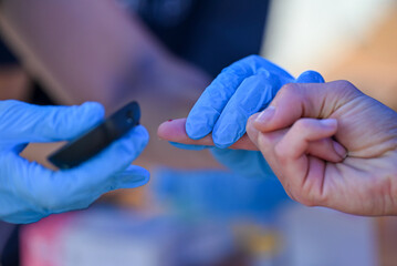 Nurse pricking a patient's finger to perform a blood glucose test.