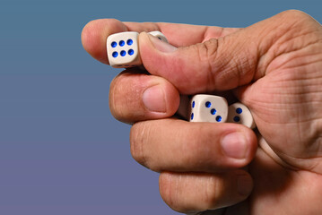 A hand holding betting dice with the number 6 appearing.