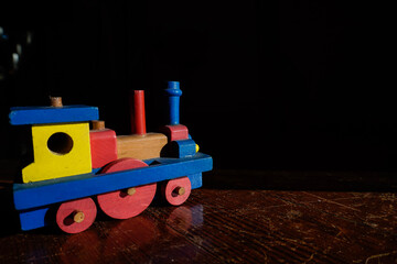 Fototapeta premium Tren de juguete de madera con color azul y rojo y amarillo, con fondo negro, objeto artesana