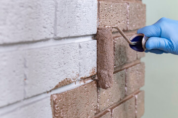 Person painting over a grey brick wall with rose gold metallic paint using a paint roller. Do it...