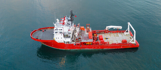 Side profile aerial view of a red specialized research vessel in the open sea showcasing its industrial design and maritime capabilities for offshore operations and transport