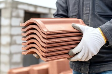 construction worker carry clay roof tile stack. Roofing material and installation