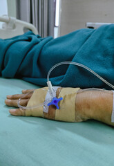 Close up of a patient hand with an IV drip for medical treatment in a hospital setting.
