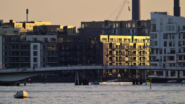 People cycling and walking on Lille Langebro bridge over Copenhagen harbor at sunset