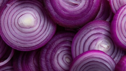 Obraz premium Fresh red onions are cut into thin round slices and placed closely together. The light reveals their vibrant colors and unique patterns on a flat surface.