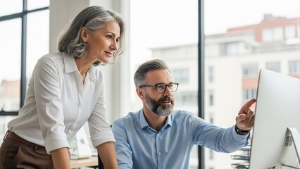 Two professional colleagues collaborating and discussing work in a modern office setting.