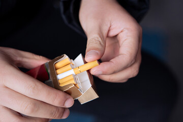 A man holds a pack of cigarettes in his hands, 