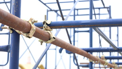 Scaffolding pipe clamp. Swivel clamp holds metal scaffolding pieces on construction sites or outdoor stage structures and provides copy space with selective focus.