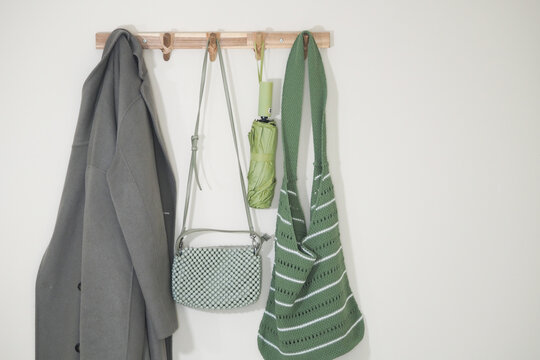 Coat and bags hanging on a wall hook in a bright room