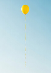 A solitary vibrant yellow balloon with a long ribbon floats high in a clear serene blue sky symbolizing joy.
