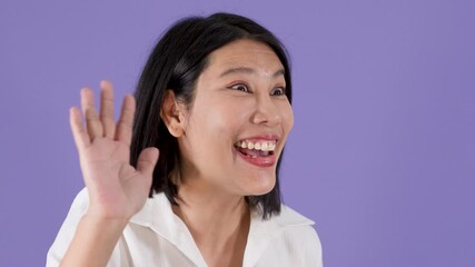 Happy Asian Woman Smiling and Waving Hand Against Purple Background