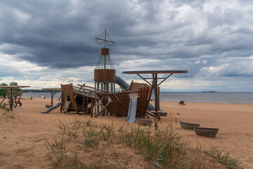 Children's playground in the shape of a ship on a sandy beach on the Baltic Sea coast on a sunny summer day, Sestroretsk, Kurortny district, Saint Petersburg, Russia