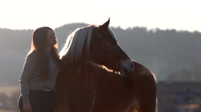 Young woman cuddling and bonding with her Haflinger mare outdoors