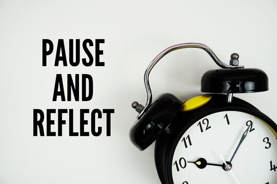Pause And Reflect text with alarm clock flat lay on white background