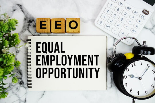 EEO Equal Employment Opportunity text with calculator and alarm clock on marble background
