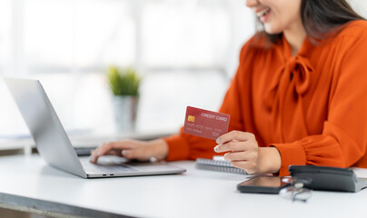 Digital Payment Delight: A woman's smile radiates as she expertly navigates an online transaction, cradling a credit card with anticipation, seamlessly integrating into the era of digital commerce.