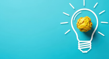Elevated view of a crumpled yellow paper ball inside light bulb shape over blue background represents creative idea concept. It symbolizes innovation and inspiration.