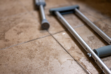 Crutches placed on wet floor in a building during the day after an accident or injury
