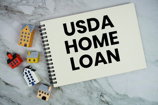 USDA Home Loan text written on notepad with house model on marble background