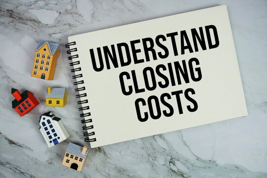 Understand Closing Costs text written on notepad with house model on marble background