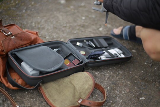 Open drone case on the ground with a drone, remote controller, and accessories neatly arranged inside, professional aerial equipment setup outdoors