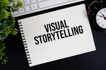 Visual Storytelling text written on notepad with keyboard and alarm clock on black background