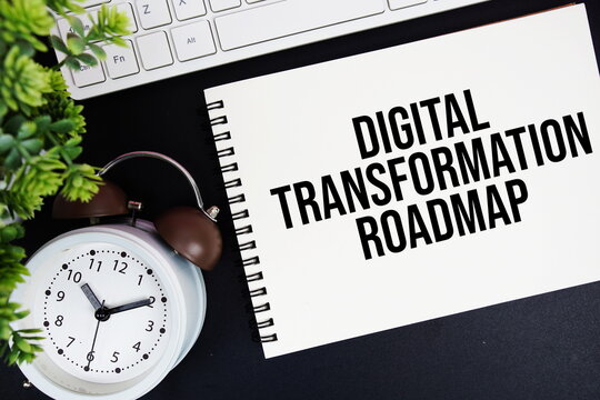Digital Transformation Roadmap text written on notepad with keyboard and alarm clock on black background - Powered by Adobe