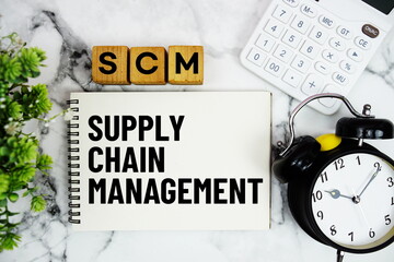SCM Supply Chain Management text with calculator and alarm clock on marble background