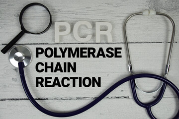 PCR Polymerase Chain Reaction text with Stethoscope on wooden background
