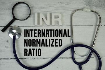 INR International Normalized Ratio text with Stethoscope on wooden background