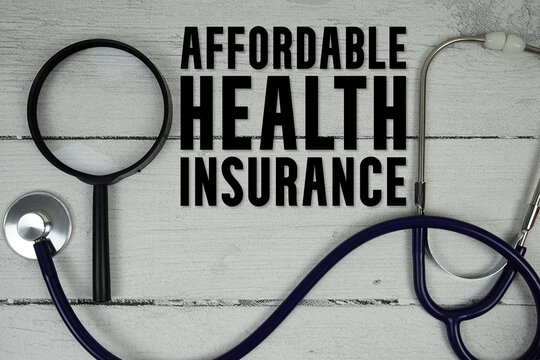 Affordable Health Insurane text with Magnifying glass and Medical Stethoscope on wooden background