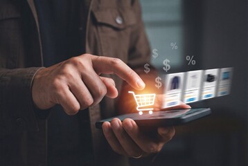 Man holding smartphone with virtual shopping cart icon and currency symbols during online purchase