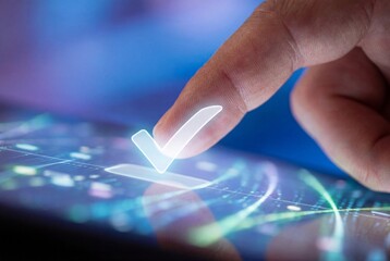 Finger touching glowing checkmark symbol on modern blue digital technology touchscreen