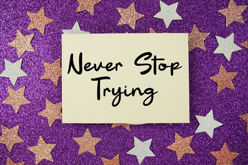 "Never Stop Trying" quotes on paper card with purple glitter background with pink and white stars