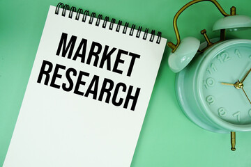Market Research text with alarm clock flat lay on green background