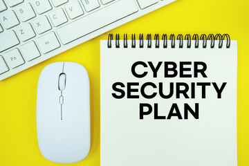 Notepad with the text "Cyber Security Plan" with white keyboard and wireless mouse on yellow background