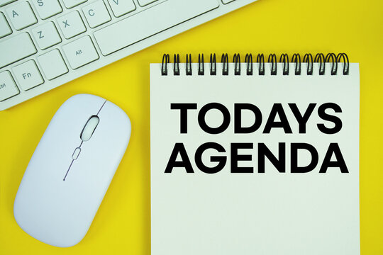Notepad with the text "Today's Agenda" with white keyboard and wireless mouse on yellow background