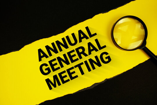 Annual General Meeting text on yellow with black paper torn ripped and magnifying glass