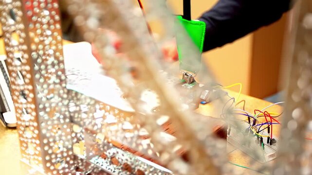 Person building a robot with wires and circuits, focused arm detail