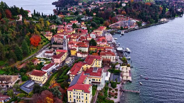 Aerial view of Bellagio on Lake Como, showcasing colorful lakeside buildings, narrow streets, and the waterfront promenade surrounded by vivid autumn trees.