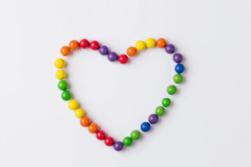 Obraz premium Rainbow heart made of round colored candies or wooden balls. Suitable for valentines day, love, romance, and candy themed designs.